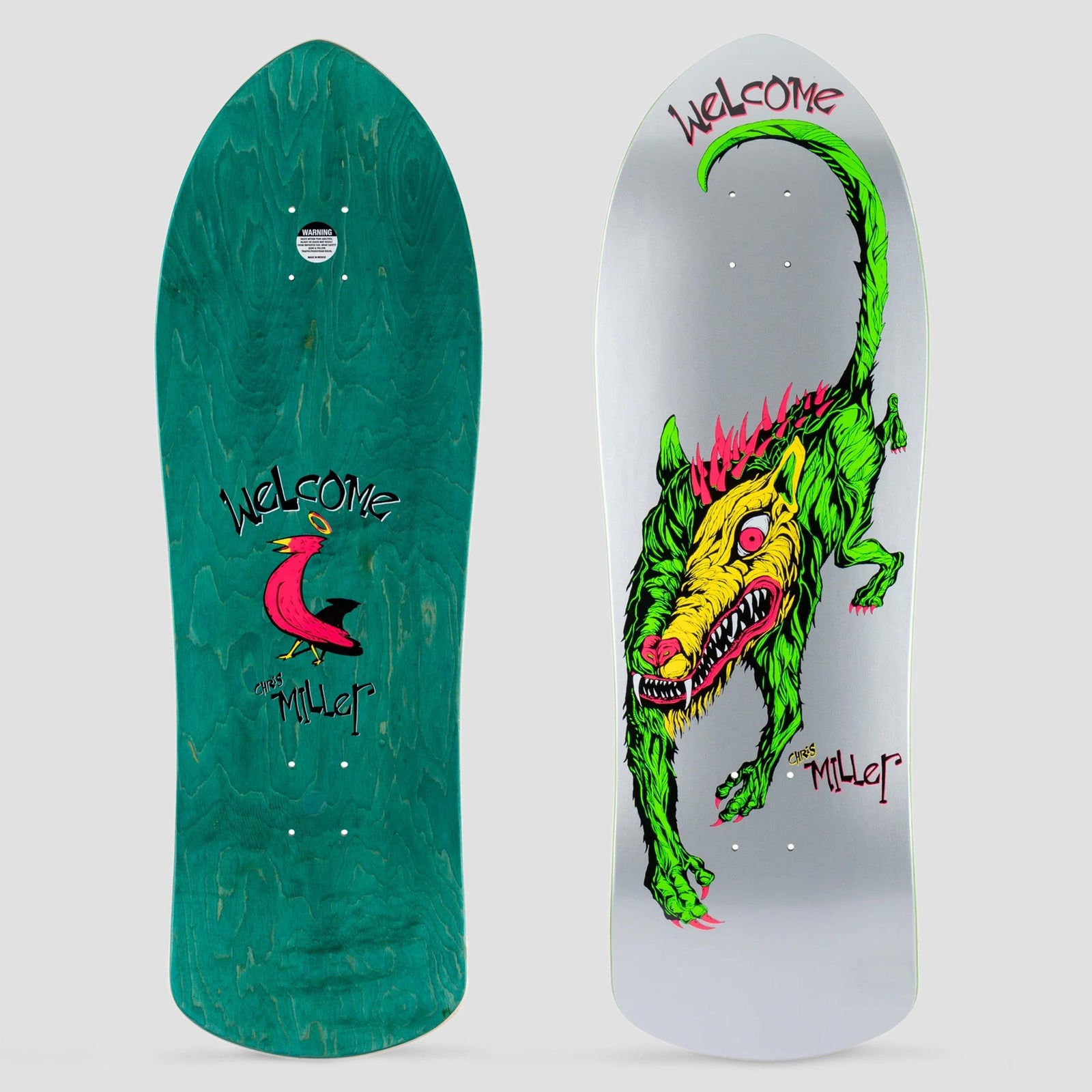 Welcome Miller Beast on Crossbone Silver skateboard deck: A green wolf-like beast with a yellow one-eyed face, red mane and long curled tail prowls across a silver old-school shaped deck. The teal underside shows a pink bird with a halo.