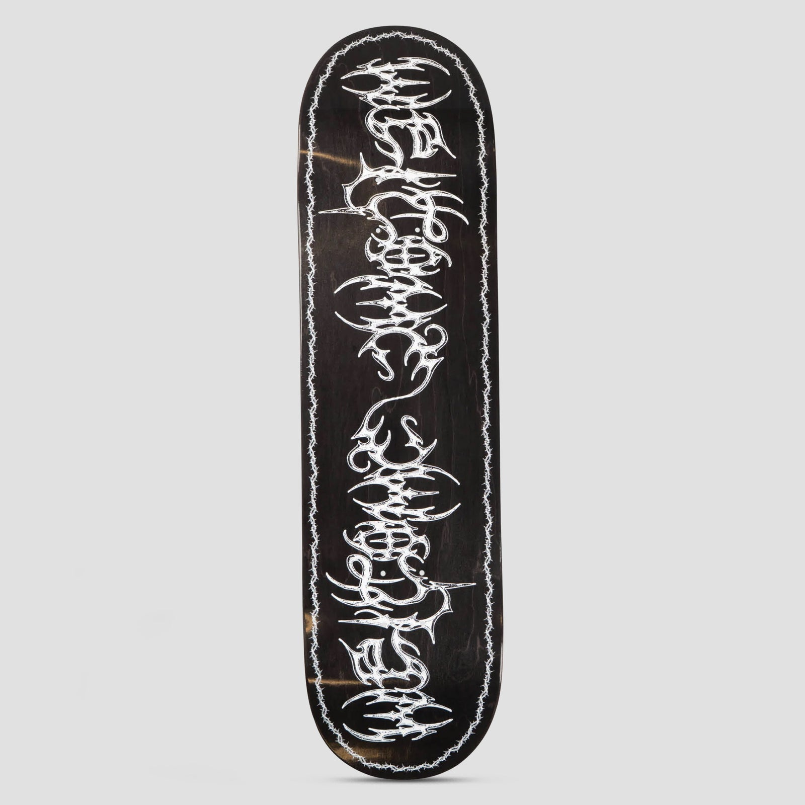 Welcome Thorn Various Stains skateboard deck: Black-stained deck with white spiky gothic metal-style lettering stacked down the length, framed by a thin barbed wire border around the edge.