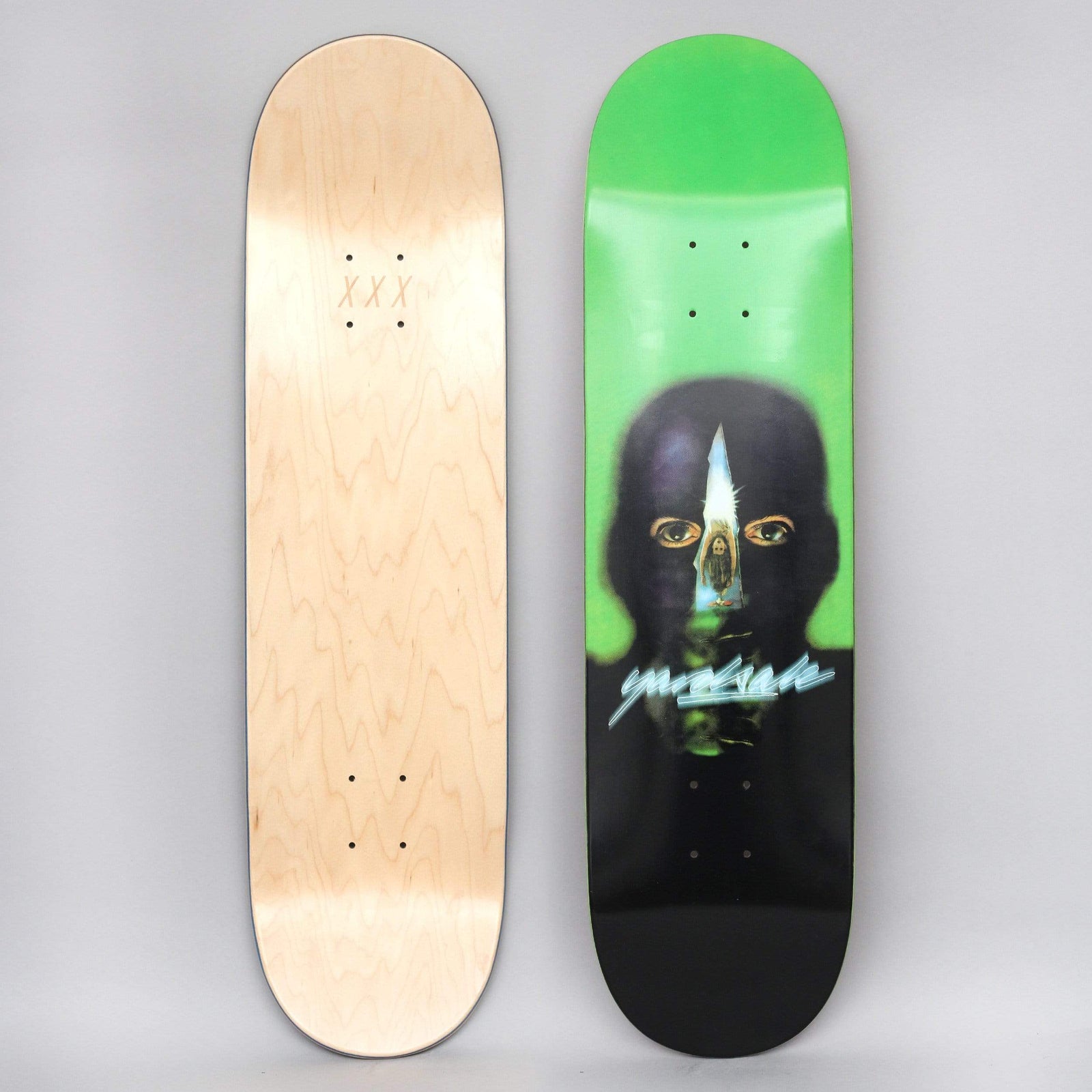 Yardsale Gnar Man Green skateboard deck: Blurred painted portrait of a dark, featureless head with staring eyes and a narrow vertical slit revealing a small figure inside, on a green and black gradient. A chrome script logo crosses the neck.