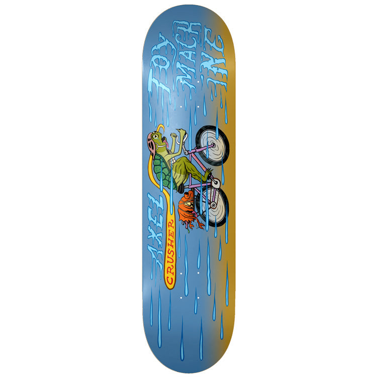 Toy Machine Axel Cruysberghs Cyclist 8.25 skateboard deck: A green turtle in a pink helmet rides a pink bicycle, with an orange one-eyed monster beneath, through blue rain on a blue and ochre deck. Dripping blue lettering for the brand and rider name, and Crusher on a yellow banner.