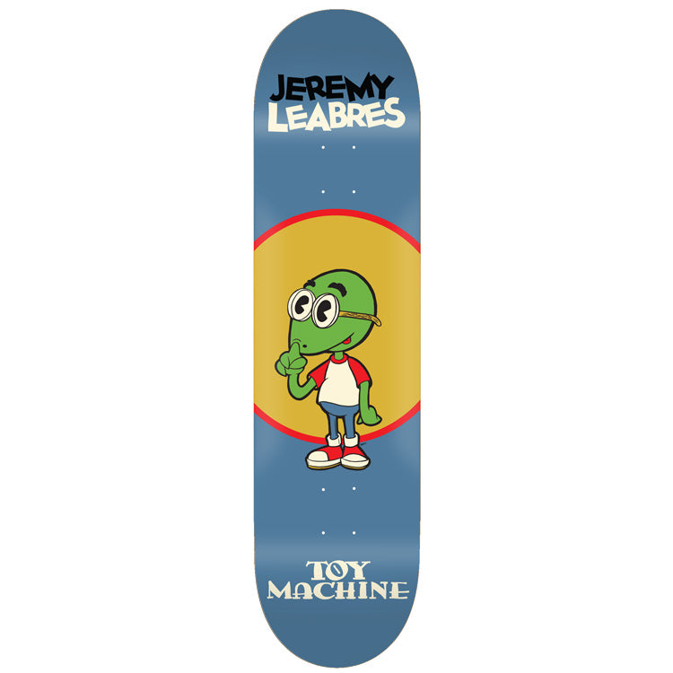 Toy Machine Jeremy Leabres Toons 8.50 skateboard deck: Cartoon green turtle-like character with big round glasses in a white and red shirt, raising a finger to his nose, in front of a yellow circle with red ring on a blue deck. Name at top, Toy Machine below.