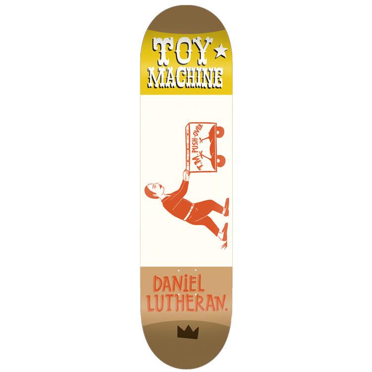 Toy Machine Daniel Lutheran Kilgallen 8.38 skateboard deck: A simple orange illustration of a man in a suit carrying a wheeled box marked 'T.M. Push-Over' on a cream panel, between a yellow band with 'Toy Machine' lettering at the nose and brown at the tail. A small black crown sits at the tail.