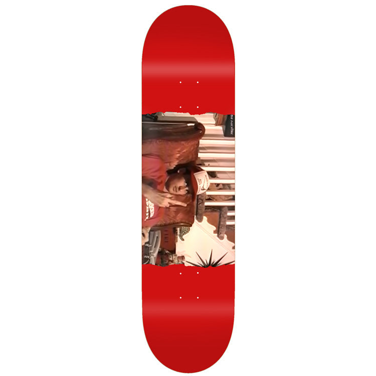 Toy Machine Ed Templeton Flip 8.50 skateboard deck: A rotated colour photograph of a person in a red top and cap, sitting in an ornate chair with a hand raised, printed as a band across a plain red deck. A small spiky starburst sits at the lower edge.