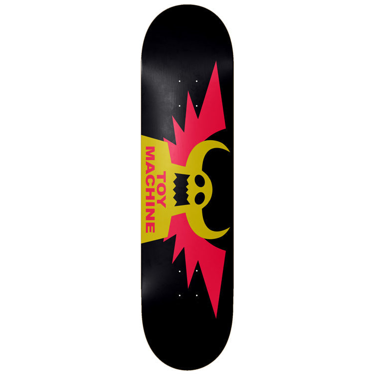 Toy Machine Winged 8.50 skateboard deck: Toy Machine's horned monster face logo with jagged pink wings spreading either side, on black. The brand name runs vertically in pink on a gold block below the face.