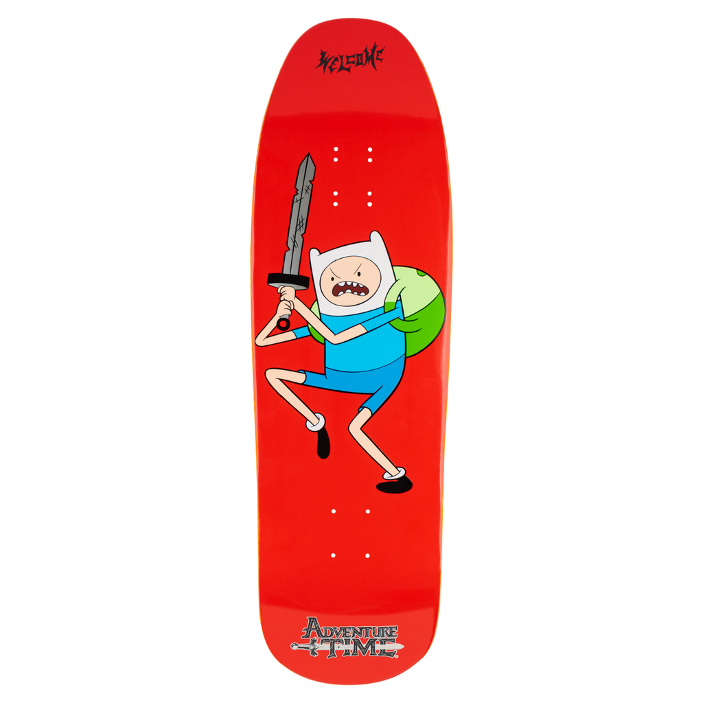 Welcome ADVENTURE TIME X WELCOME - Finn on Gaia skateboard deck: Finn the Human, in a white hat and blue outfit with a green backpack, leaps with a grey sword raised and an angry shout on a bright red shaped deck. Welcome lettering is at the nose and Adventure Time at the tail.