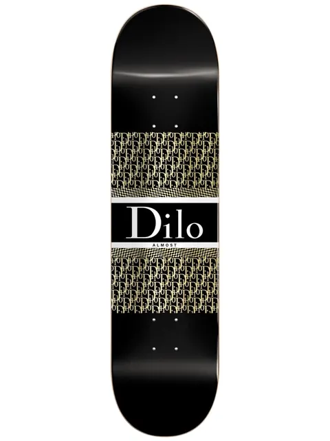 Almost Dilo Luxury Super Sap R7 8.125 skateboard deck: Black deck with a luxury fashion-label parody: a white-bordered black panel with serif "Dilo" in white, between two bands of repeating gold monogram lettering.