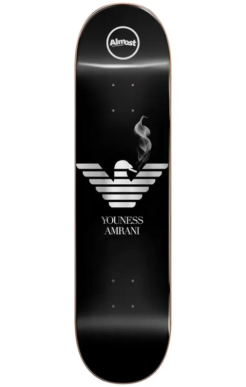 Almost Youness Runway R7 8.25 skateboard deck: Black deck with a silver striped eagle emblem in the manner of a fashion label logo, a wisp of smoke rising from its head. The rider name is in serif capitals beneath, with the round Almost logo at the nose.