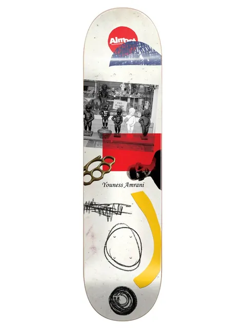 Almost Youness Scraps R7 skateboard deck: Collage on a white deck: a black and white photo of small fountain statues in a shop window, brass knuckles, a red block, a dark portrait fragment, scribbles, a yellow arc and a red Almost logo circle.