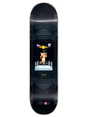 Almost Yuri Gronze Collab R7 8.3 skateboard deck: Dark navy deck with faint architectural columns and ornaments, and a small cherub with halo and red boxing gloves in a boxing ring, with a championship belt and two doves above. Yuri in gold text.