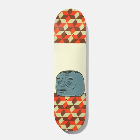 Baker Spanky Barry 8.5 skateboard deck: Grumpy blue-grey blocky head with a lined face and open mouth, drawn in a folk-art style, sitting on a cream band between two panels of isometric cube pattern in orange, brown and pale green.