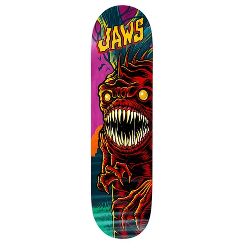Birdhouse Jaws Graveyard 8.475 skateboard deck: A red scaly monster with spiked head, glowing yellow eyes and a huge mouth of fangs climbs over a fence post, against a magenta and teal night graveyard scene. Yellow 'Jaws' lettering sits at the nose.