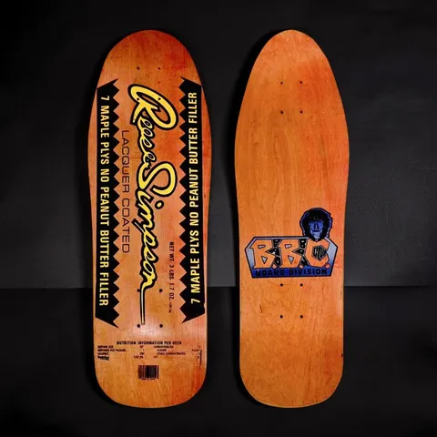 Brand-X Reese Simpson Buttercup skateboard deck: Old-school shape on orange stain styled as a peanut butter jar label: yellow script Reese Simpson name, black zigzag-edged panels reading 7 maple plys no peanut butter filler, nutrition panel and barcode. The underside shows a B.B.C. Board Division logo with a portrait.