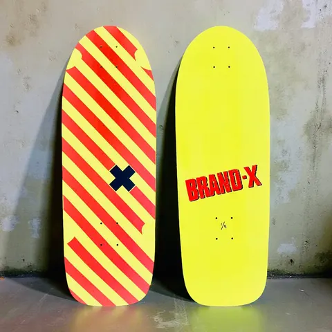 Brand-X Vertical Hold skateboard deck: Old-school shaped yellow deck with diagonal red stripes and a small navy cross in the middle; the underside is plain yellow with red BRAND-X lettering and 1/5 edition mark.