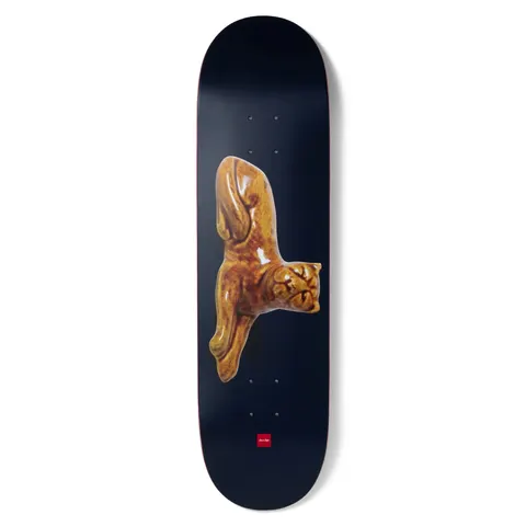 Chocolate Aikens Porcelain skateboard deck: A glossy, honey-brown glazed porcelain figure of a stretching cat, photographed against a dark navy deck. A small red Chocolate logo sits near the tail.