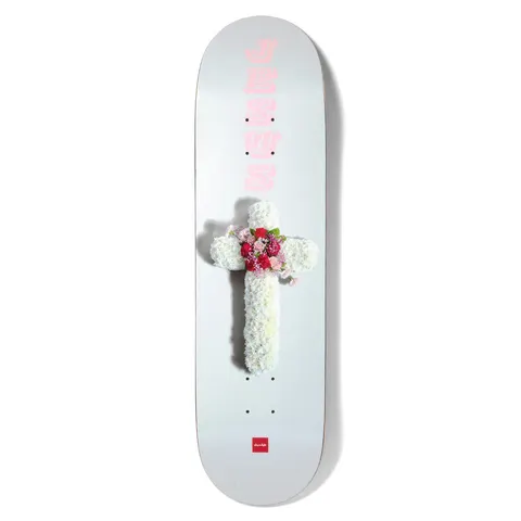 Chocolate Fernandez Flower Cross skateboard deck: A photographed funeral-style floral cross of white carnations with a red and pink flower centre on a pale grey deck. The word JESUS is stacked vertically in pink above it, with a small red Chocolate logo at the tail.