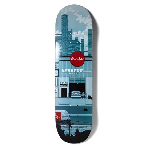Chocolate Herrera Pixel City skateboard deck: Pixel-art city scene in blue-grey tones: factory chimneys with smoke above a garage front with a red Chocolate logo sign and Herrera Auto + Body lettering, a truck inside and a van on the street below.