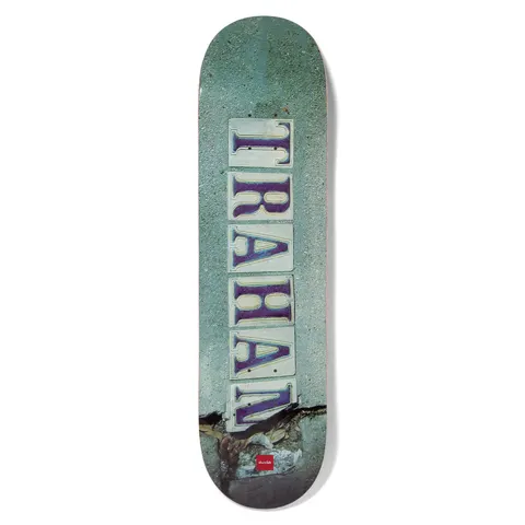 Chocolate Trahan French Quarter skateboard deck: Photographic image of a pavement with a row of old street-name tiles spelling 'TRAHAN' vertically in purple serif letters, with a crack across the concrete at the bottom.