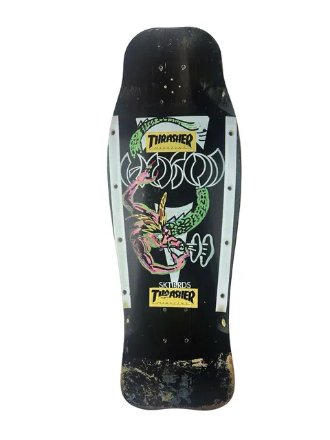 Hosoi Dragon skateboard deck: Worn black old-school shaped deck with a green and pink dragon coiled around Hosoi lettering in white outline, with white side panels and two Thrasher magazine stickers. The tail is badly scuffed.