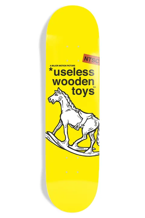 New Deal Useless Wooden Toys Ntsc skateboard deck: Black line drawing of a white rocking horse on a plain yellow deck, with 'useless wooden toys' in bold black type, a small 'A major motion picture' line and a red-orange NTSC tag.