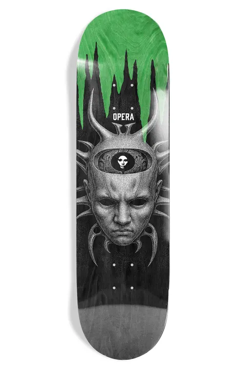 Opera Trey Wood Spider skateboard deck: Greyscale engraving-style stone-faced head with horned, spiky spider-like legs and an open skull top revealing a smaller masked face. Green slime drips across the nose end of the black deck.