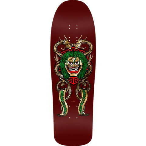 Powell Peralta Caballero Mask Burgundy skateboard deck: A grinning demon mask with green hair and fangs sits over a red geometric emblem, flanked by two gold bone-dragon snakes holding banners with green lettering, on a burgundy old school shaped deck.