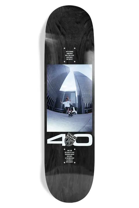 Shut Bryce Kanights Bruno EX7 skateboard deck: Fisheye photograph of a skater mid-trick between two towers of a tall twin-tower complex, in a panel on a black deck, with a large white 40 and a crest below and small credit text.