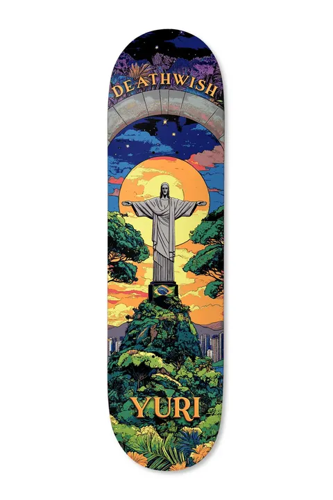 Deathwish Yuri The Redeemer 8.25 skateboard deck: Comic-style illustration of the Christ the Redeemer statue on a forested hill at sunset, with a Brazilian flag on the plinth, city below and a stone arch with the brand name at the top. YURI in orange at the tail.