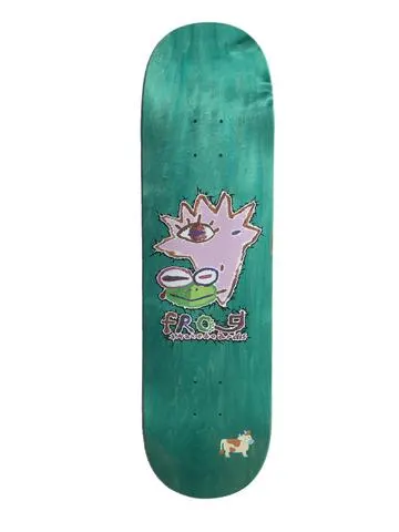 Frog Painted Logo 8.5 skateboard deck: Teal stained deck with a crude, childlike painted face: a pink spiky head with one eye and a green frog mouth, with a hand-lettered Frog logo beneath. A small cartoon cow sits near the tail.
