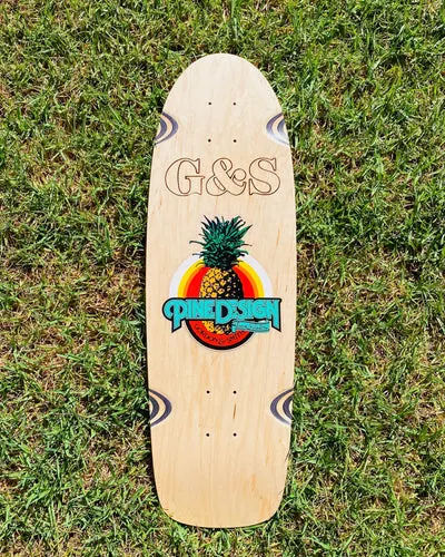 G&S 30 Original Pine Design - Natural skateboard deck: Natural wood old-school cruiser shape with a G&S outline logo burned at the top and a Pine Design logo with a pineapple over rainbow arcs. Four wheel-well swirls sit at the corners.