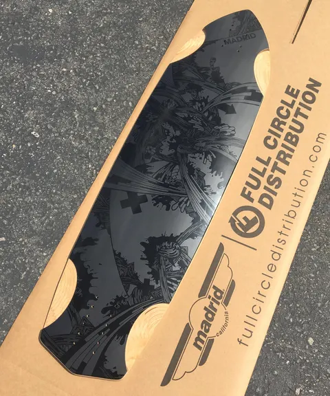 Madrid Factory Exclusive - Kraken 37 skateboard deck: Cruiser deck with wheel cutouts and a glossy black-on-black tonal illustration of tangled, swirling tentacle-like forms and splatter, with a Madrid logo at the nose. Shown in a cardboard shipping box.