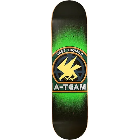 A-Team Chet Thomas Crest skateboard deck: Circular crest in green and gold with a yellow stylised bird of prey over a dark blue wheel emblem, on a black deck with a glowing green spray fade. Rider name curves round the top and A-TEAM sits on a silver banner below.