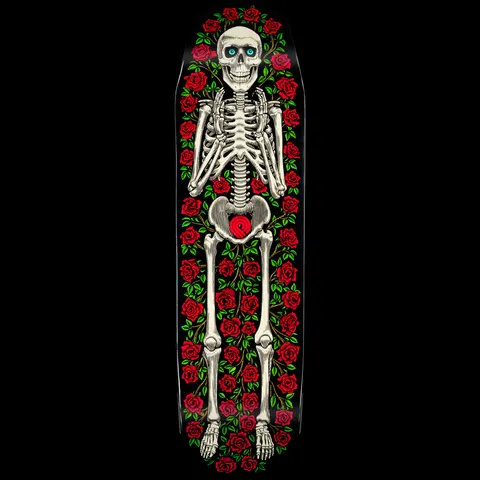 Powell Peralta Casket Funshape skateboard deck: A smiling skeleton with turquoise eyes lies full length, surrounded by red roses and green leaves, with a red rose over the pelvis, on a black deck.