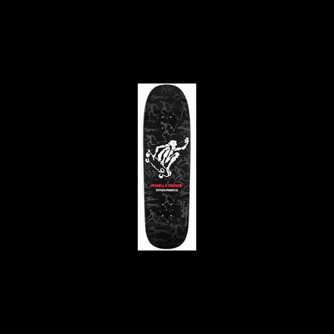 Powell Peralta Future Primitive skateboard deck: A white tribal figure skating in a crouched pose with an arm raised, above a faint grey pattern of many small skating figures, on a black deck. Powell Peralta and Future Primitive text below.