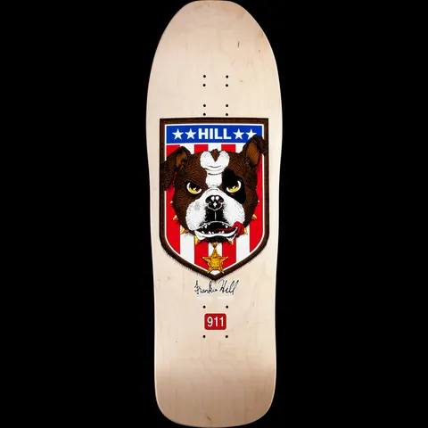 Powell Peralta Hill Bulldog Natural skateboard deck: Bulldog head with spiked collar and sheriff's star badge, set inside a shield with red and white stripes and a blue star band. Signature below and a red 911 badge near the tail, on a natural wood deck.