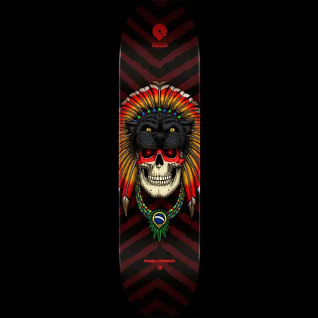 Powell Peralta Pro Kelvin Hoefler Skull - Shape 247 skateboard deck: Colour illustration of a human skull with red eyes wearing a black panther headdress and a feathered war bonnet in red, orange and yellow, with a beaded necklace bearing a Brazilian flag pendant, on a black and maroon chevron background.