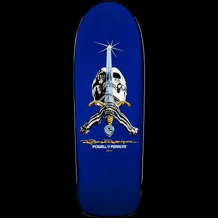 Powell Peralta Ray Bones Skull and Sword Blue skateboard deck: Old-school shaped blue deck with a skull and skeletal hands gripping a sword that points upward with a sparkle at its tip, with a gold Ray Bones signature and the Powell Peralta logo below.
