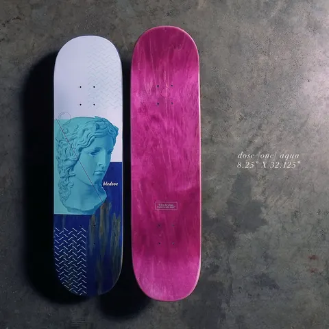 Quasi Dose - Aqua skateboard deck: White-topped deck with an aqua-tinted classical marble bust head, over a deep blue lower section with drip marks and zig-zag line patterns. Rider name at the bottom; magenta stained underside shown alongside.