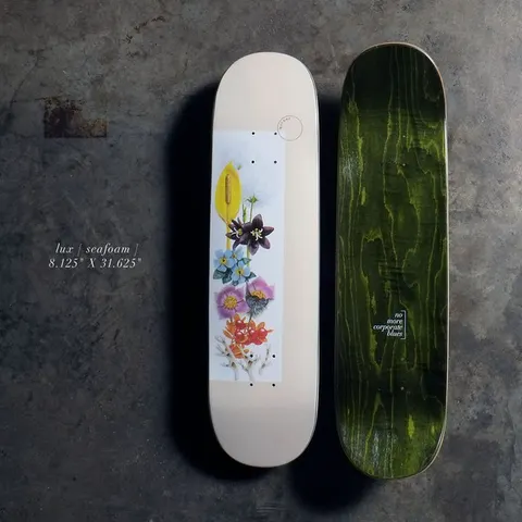 Quasi Lux8.125 - Crème skateboard deck: A cream deck with a white panel of botanical flower illustrations in yellow, purple, blue, pink and orange, stacked up the centre, with a small circle logo above. The underside is dark green stained wood with small text.
