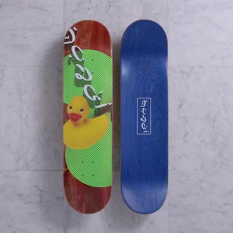 Quasi Ducking Red skateboard deck: Yellow rubber duck photographed in front of a green circle of concentric lines, with white Arabic-style script lettering running down a red stained deck. Underside is blue with a boxed script logo.