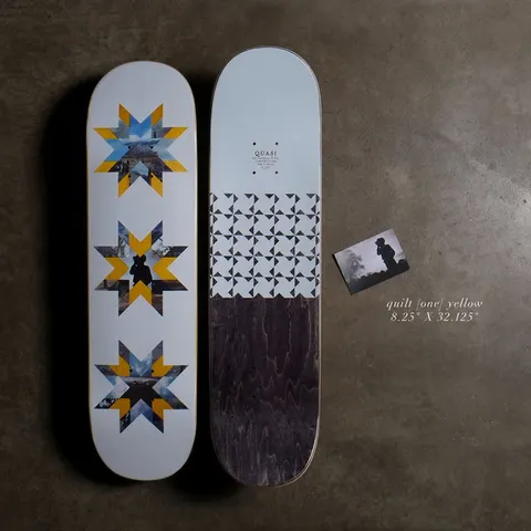 Quasi Quilt - Yellow skateboard deck: Three star-shaped quilt patterns made from landscape photographs and yellow segments, on a pale blue deck. A second deck shows triangle patterns and a dark stained lower half, with a small photo card.