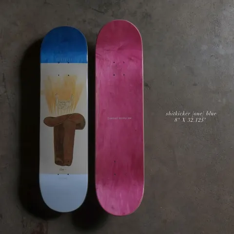 Quasi Shitkicker 8 - Blue skateboard deck: Painted brown cowboy saddle with a glowing yellow animal skull above it, on a cream panel between a blue top and pale blue base. A second deck shows a plain pink stained underside with small text.