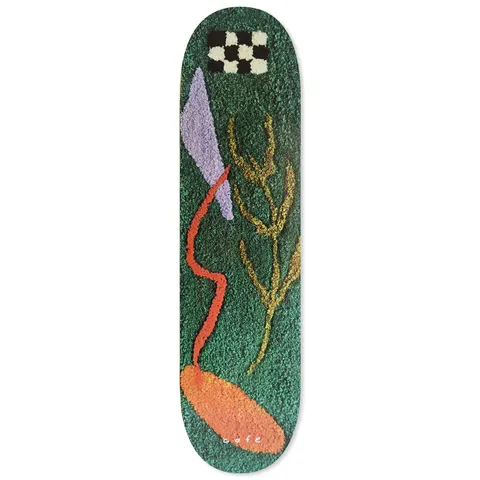 Skateboard Cafe April - Dark Teal skateboard deck: Abstract tufted rug-style artwork on dark green: a black and cream checkerboard patch, a lilac shard, a wavy red-orange line ending in an orange oval, and a gold branch. Small 'cafe' logo at the bottom.