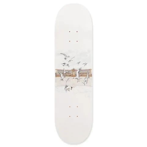 Skateboard Cafe Lloyds White skateboard deck: Delicate illustration of seagulls flying and landing in front of a large seafront building and promenade, in muted greys and sepia, on a plain white deck. Small 'Cafe' text at the lower right.