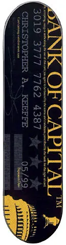 Capital Bank Of Capital skateboard deck: Black deck styled as a bank card, with a gold vertical Bank of Capital title, a long card number, cardholder name, expiry date, three stars and a gold US Capitol dome at the foot.