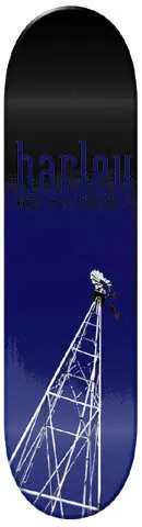Toy Machine Donnny Barley Windmill skateboard deck: A tall white lattice windmill tower with a small figure at its top rises from the base of a deck fading from black to deep blue. The rider's surname is in large blue lowercase text near the top with small text beneath.