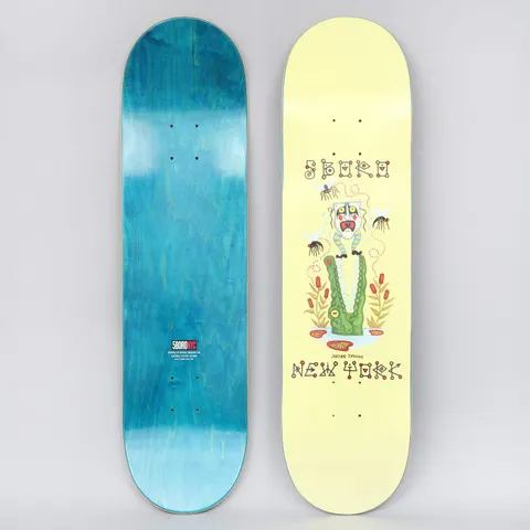 5Boro X Ds 8.25 Jordan Trahan Yellow skateboard deck: A green crocodile with open jaws holds a white-faced mask figure with a striped headdress, swatted at by mosquitoes among cattails. 'Jordan Trahan' appears above lettering reading '5Boro' and 'New York' on a pale yellow deck.
