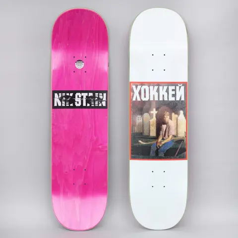 Hockey Nik Stain White skateboard deck: A framed painting-style image of a boy holding a hockey stick in a graveyard with crosses and gravestones, headed by XOKKEЙ in white capitals on a red panel, on a white deck. The pink underside has a NIK STAIN banner over eyes.