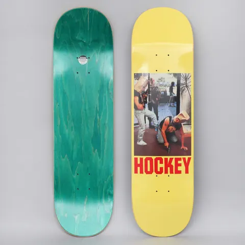 Hockey Baghead 2 Yellow skateboard deck: A colour photograph of two men in a street doorway with paper bags over their heads, one crouching and holding a handgun, in a rectangular panel on a yellow deck. The brand name is in red capitals underneath. The teal-stained underside is shown too.