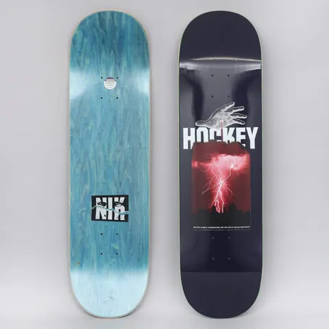 Hockey Stain Side Two Navy skateboard deck: Navy deck with a pale hand reaching down towards a bold white Hockey logo, over a red-tinted photo of a lightning storm above a city skyline. Small caption text beneath; the bottom shows a blue-stained deck with an NK logo.