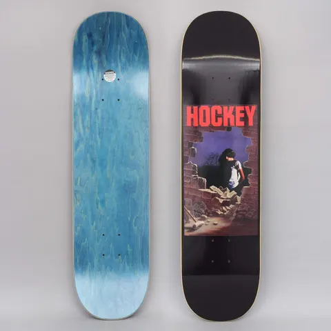 Hockey Donovon Piscopo Dawn Black skateboard deck: Painted panel of a dark-haired person in a white t-shirt standing in a hole smashed through a brick wall, with rubble and a sledgehammer on the floor. A red Hockey logo sits above, on black.